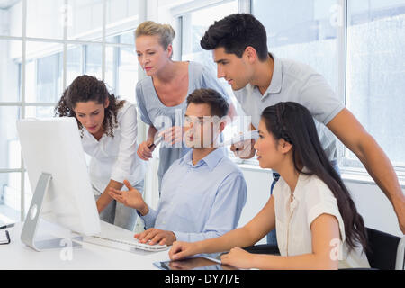 Imprenditore informale che mostra i colleghi qualcosa sul computer Foto Stock