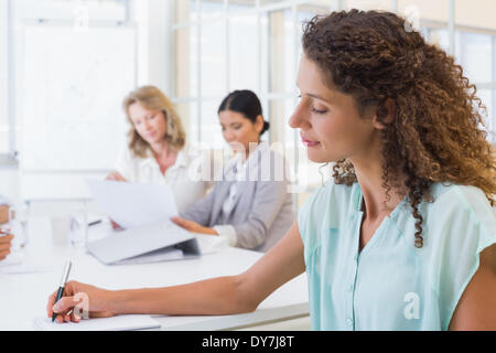 Casual imprenditrice prendere appunti durante la riunione Foto Stock