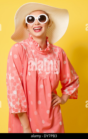 Breve capelli biondi donna,Caucasian modello femminile in posa di studio contro sfondo giallo, un vintage fashion concept Foto Stock