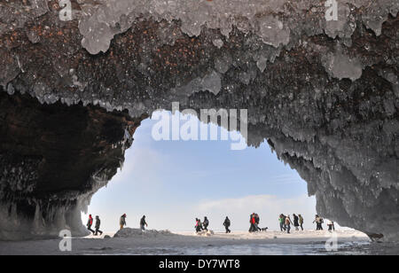 Formazioni di ghiaccio e ghiaccioli pendenti dal soffitto in una grotta e la gente che camminava sul lago ghiacciato di Superior, Apostle Islands National Foto Stock