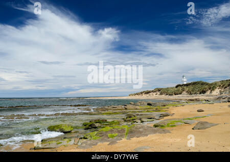 Faro di Waipapa punto con le nuvole nel cielo, spiaggia sabbiosa con alghe rocce coperte nella parte anteriore, Otara, Fortrose Foto Stock