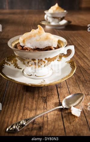 Cotta mandorle Moka Cup cake con tappo di meringa e un cucchiaio da tè sul tavolo di legno Foto Stock