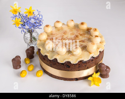 Simnel cake su uno sfondo luminoso con pieghe di marzapane un nastro giallo con 11 palline di marzapane al cioccolato fiori pulcini(26 di 35) Foto Stock