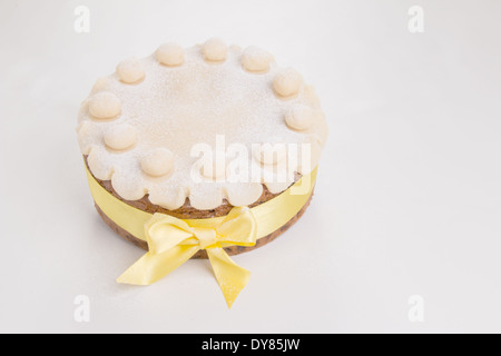 Simnel cake con del marzapane base decorazione con un nastro giallo intorno esso spolverati con zucchero a velo(16 di 35) Foto Stock