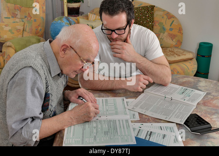 Nipote aiutando il suo nonno facendo dichiarazione fiscale Foto Stock