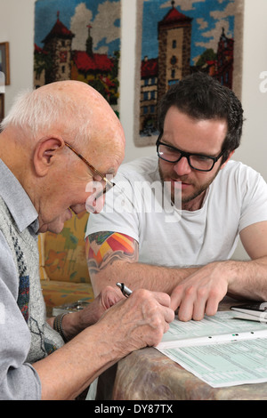 Nipote aiutando il suo nonno facendo dichiarazione fiscale Foto Stock