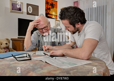 Nipote aiutando il suo nonno facendo dichiarazione fiscale Foto Stock