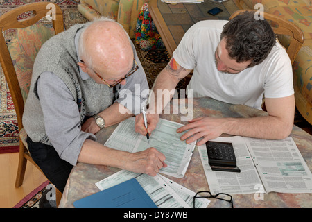 Nipote aiutando il suo nonno facendo dichiarazione fiscale Foto Stock