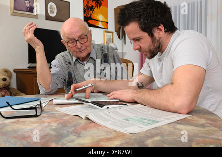 Nipote aiutando il suo nonno facendo dichiarazione fiscale Foto Stock