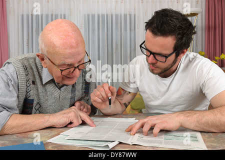 Nipote aiutando il suo nonno facendo dichiarazione fiscale Foto Stock