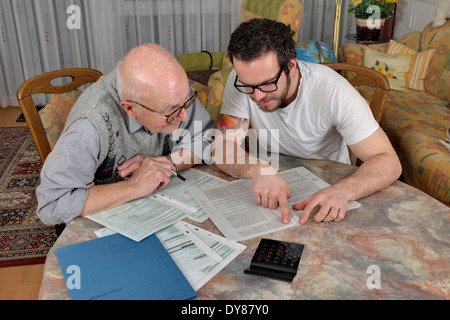 Nipote aiutando il suo nonno facendo dichiarazione fiscale Foto Stock