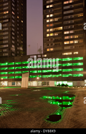 Urban astratta, luci verdi di un multipiano parcheggio con riflessi sull'acqua dopo la pioggia durante la notte . Foto Stock