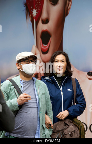 I turisti asiatici con maschera facciale di inquinamento di usura sulla strada, Un tabellone pubblicitario dietro di loro, Repubblica Ceca di Praga Foto Stock