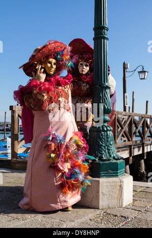 Coppia in splendidi abiti fantasiosi costumi e maschere che pongono la laguna durante il carnevale di Venezia il Carnevale di Venezia, Italia Foto Stock