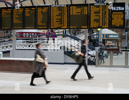Persone sfocate fretta per prendere il treno sotto Schede destinazione Newcastle upon Tyne station North East England Regno Unito Foto Stock