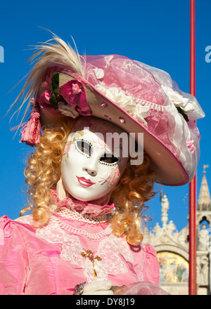 Ritratto di signora mascherato in abito rosa e hat contro il cielo blu in posa durante il carnevale di Venezia Foto Stock