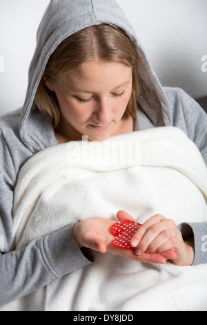 Giovane donna ha un freddo, warm up con un pacco di calore Foto Stock