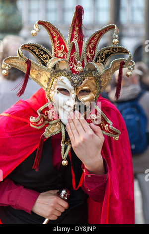 Arlecchino in costume o jester con maschera sorride alla macchina fotografica durante il carnevale di Venezia, Carnevale di Venezia, Italia Foto Stock