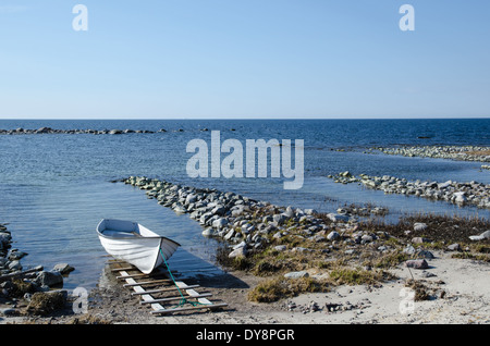 Unico ormeggiate le barche a remi a una costa rocciosa Foto Stock