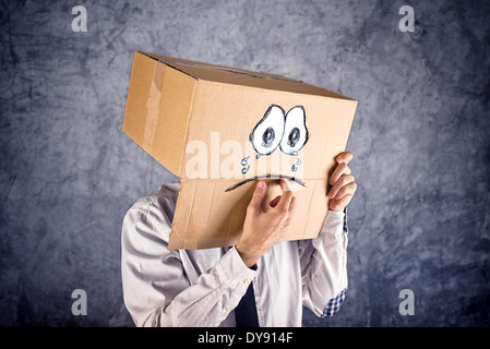 Imprenditore con scatola di cartone sulla sua testa e tristi lacrime di espressione. Concetto di tristezza e depressione. Foto Stock