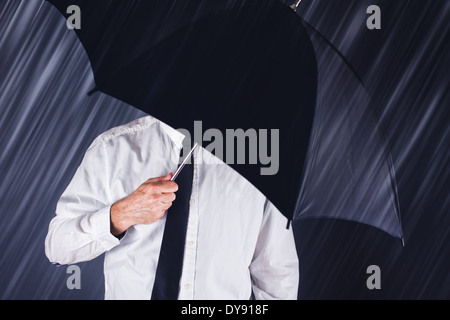 Imprenditore con ombrello nero la protezione dalla pioggia. Il concetto di business per la protezione, la sicurezza in tempi difficili. Foto Stock