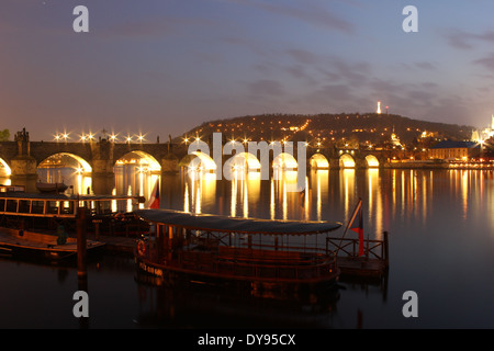 Il famoso Ponte Carlo / Karlsbrücke da notte e illuminato con navi a Riverside, Praga, Repubblica Ceca, Europa Foto Stock