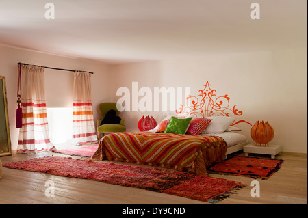 Warm indiano e il Marocco ha ispirato la camera da letto con tessuti in colori vivaci e calcinate pavimenti in legno di quercia Foto Stock