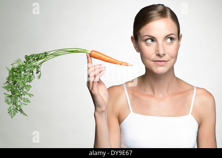 Giovane donna tenendo su materie carota Foto Stock