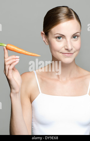 Giovane donna tenendo su materie carota Foto Stock