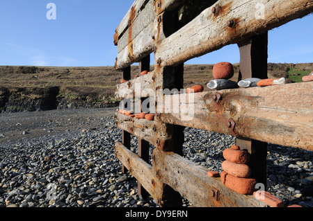 Ciottoli e lavato fino vecchi mattoni locali sulla tempesta danneggiato per la difesa del mare Abereiddi Pembrokeshire Wales Cymru REGNO UNITO GB Foto Stock