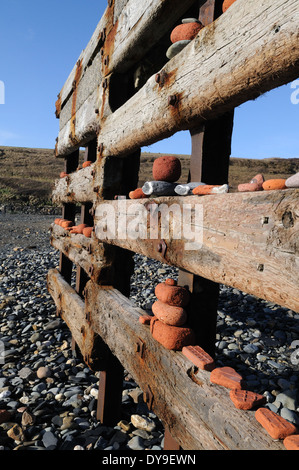 Ciottoli e lavato fino vecchi mattoni locali sulla tempesta danneggiato per la difesa del mare Abereiddi Pembrokeshire Wales Cymru REGNO UNITO GB Foto Stock