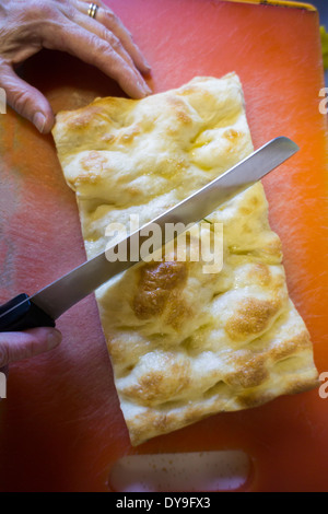 Una donna taglia una fetta di pizza bianca nella sua cucina di New York Foto Stock