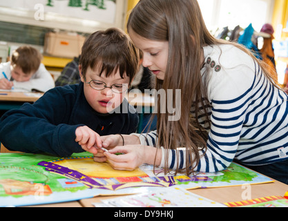 Non-disabili e gli alunni disabili (in questo caso un ragazzo che soffre di sindrome di Down) imparare insieme nella stessa classe. Foto Stock