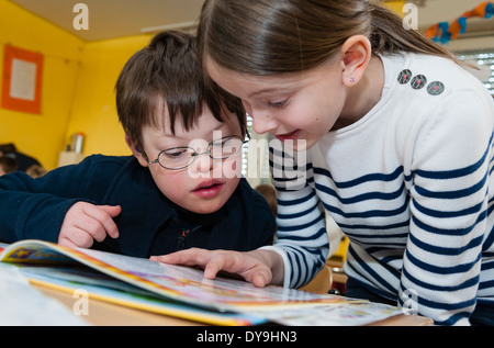 Non-disabili e gli alunni disabili (in questo caso un ragazzo che soffre di sindrome di Down) imparare insieme nella stessa classe. Foto Stock