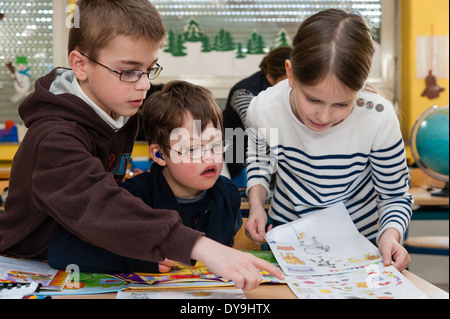 Non-disabili e gli alunni disabili (in questo caso un ragazzo che soffre di sindrome di Down) imparare insieme nella stessa classe. Foto Stock