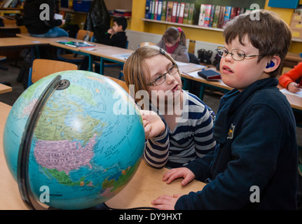 Non-disabili e gli alunni disabili (in questo caso un ragazzo che soffre di sindrome di Down) imparare insieme nella stessa classe. Foto Stock