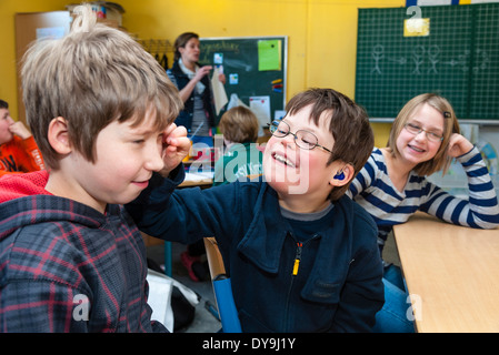 Non-disabili e gli alunni disabili (in questo caso un ragazzo che soffre di sindrome di Down) imparare insieme nella stessa classe. Foto Stock