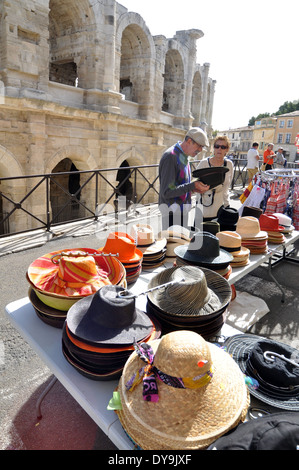 L uomo e la donna guarda cappelli in stallo nella parte anteriore del spruced-in pietra-eiettato archi dell'Anfiteatro romano di Arles Francia Foto Stock