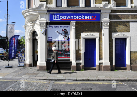 Una donna cammina passato H&T pawnbrokers shop, London, Regno Unito Foto Stock