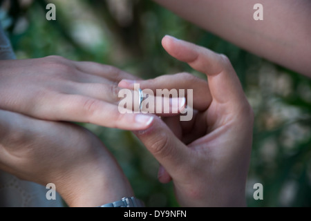 Il tempo per sposarsi, posizionando l'anello di nozze. Lo sposo di mettere l'anello sulle dita al tempo del fidanzamento Foto Stock