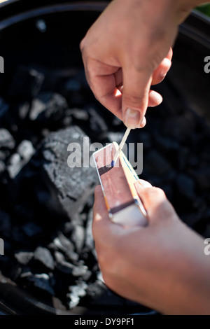 Colpisce un matchstick, masterizzare fino a carbone di legna per barbecue, preparare per la cottura Foto Stock