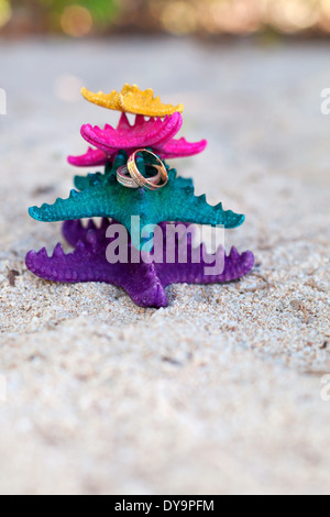 Oro anelli di nozze su colori starfishes sulla spiaggia bianca. Wedding Concetto di vacanza Foto Stock