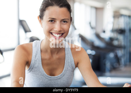 Giovane donna con macchina ginnica in palestra Foto Stock