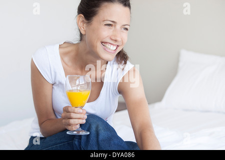 Giovane donna iniziando la sua giornata con un bicchiere di succo di arancia Foto Stock