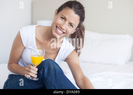 Giovane donna iniziando la sua giornata con un bicchiere di succo di arancia Foto Stock