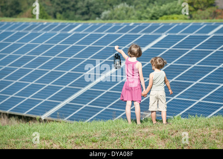 I bambini in piedi insieme nella parte anteriore dei pannelli solari, ragazza con un vecchio stile laterna Foto Stock