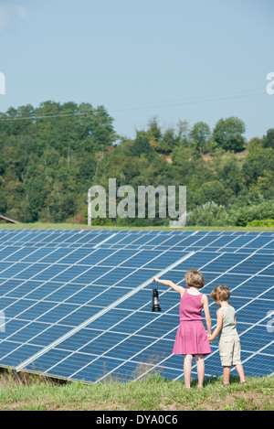 I bambini in piedi insieme nella parte anteriore dei pannelli solari, ragazza con un vecchio stile laterna Foto Stock