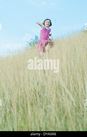 Ragazza che corre attraverso l'erba alta Foto Stock