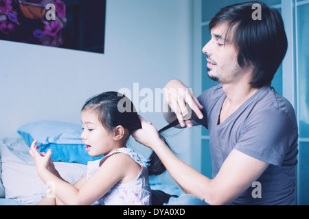 Padre mettendo figlia di capelli in coda di cavallo Foto Stock