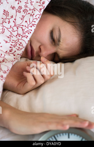 Donna giaceva a letto, la tacitazione allarme sveglia Foto Stock